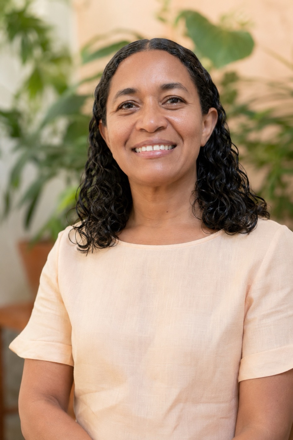 Retrato de Maria do Rosário, naturopata, sorrindo em meio a plantas